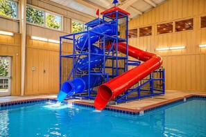 An indoor pool with a multi-level water slide structure.