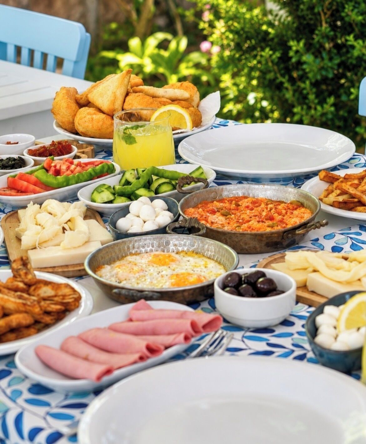 Una mesa servida con diversos platos, incluyendo comidas fritas, ensaladas y una bebida, indicando un ambiente de comida.