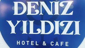 Un letrero circular con el texto 'CUNDA DENİZ YILDIZI HOTEL & CAFE' sobre un fondo blanco.