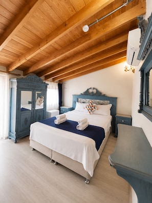 A bedroom with a wooden ceiling, a bed with white bedding, a blue dresser, and a mirror.