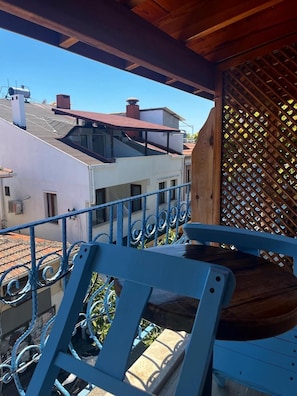 Ein Balkon mit blauem Metallgeländer und einem Holzstuhl.