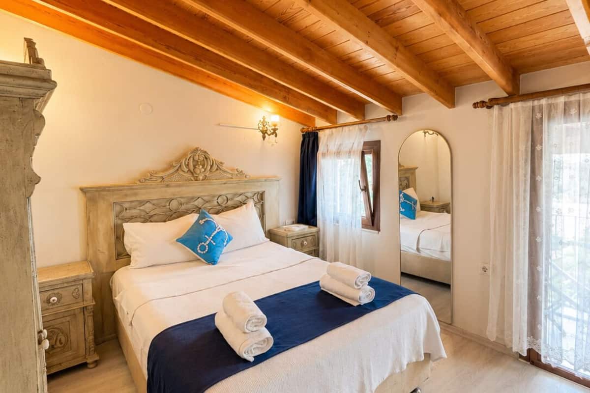 Ein Schlafzimmer mit Holzboden, einem Bett mit Kopfteil, einem Nachttisch, einem Spiegel und einem Fenster mit Vorhängen.