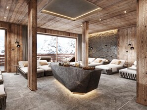 Ein modernes Interieur mit einer zentralen Kochinsel, Holzbalken, Steinwänden und Blick auf schneebedeckte Bäume.