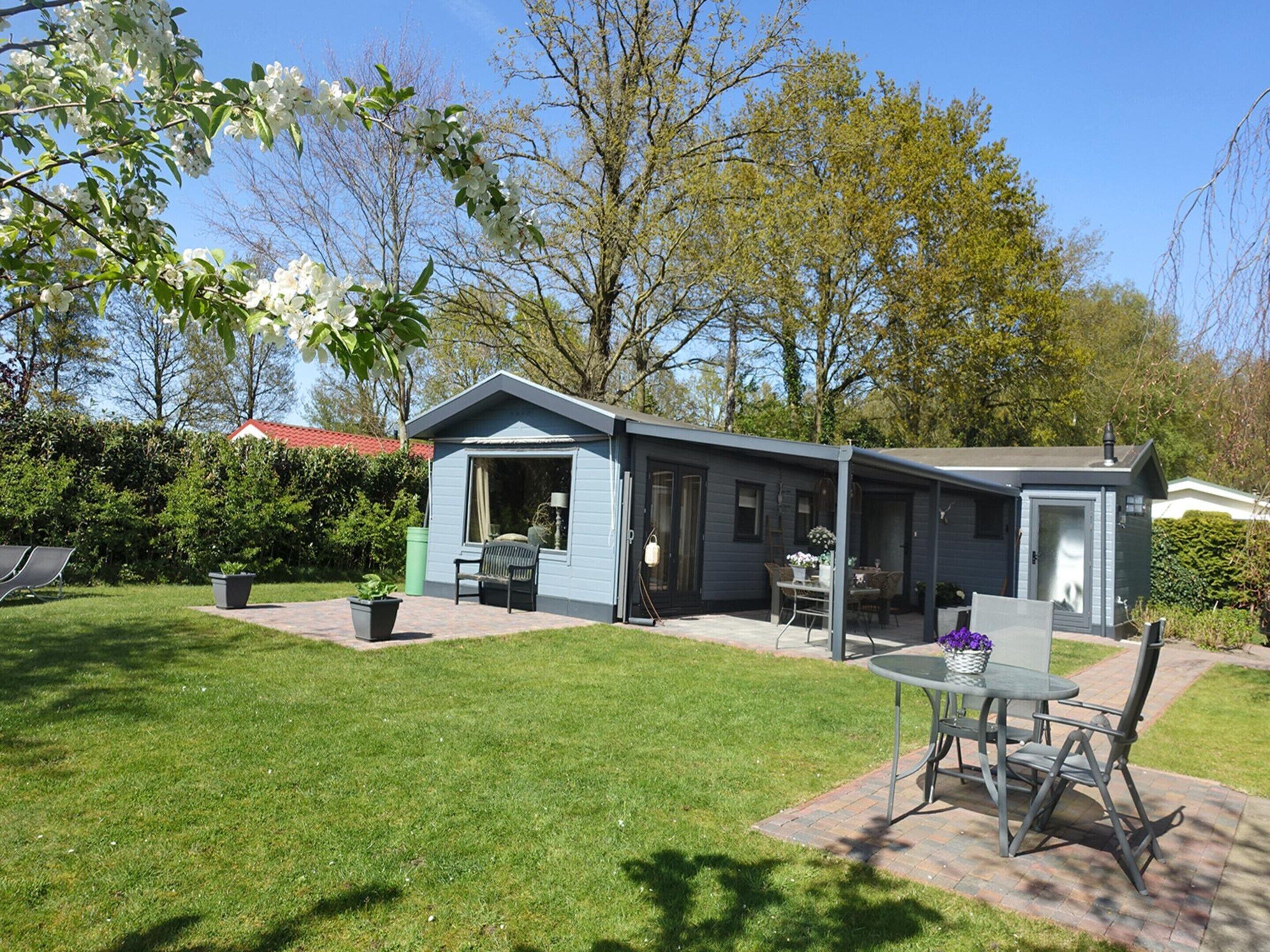 A small, single-story house with a patio, a table, and chairs.
