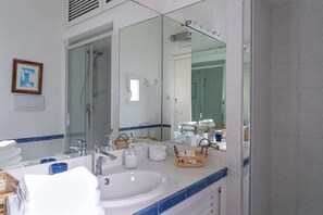Ein Badezimmer mit großem Spiegel, Waschbecken, Dusche und Handtuchhalter.