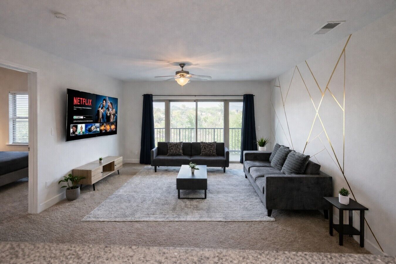 Ein modernes Wohnzimmer mit Flachbildfernseher, Sofas, Couchtisch und Deckenventilator.