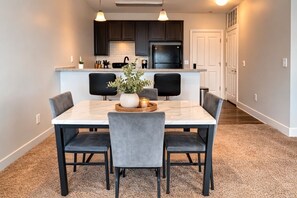 A modern kitchen with dark cabinets, a black refrigerator, and a white countertop. - Designer UAB Condo | King Bed | Balcony View D2 (Birmingham)