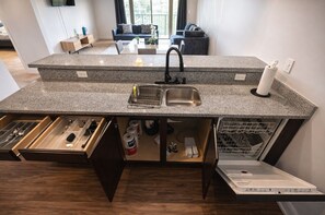A kitchen with granite countertops, a stainless steel sink, a dishwasher, and a built-in oven. - Designer UAB Condo | King Bed | Balcony View D2 (Birmingham)