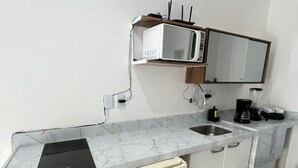 Eine kleine Küche mit integriertem Mikrowellenherd, einer Kaffeemaschine und einem Geschirrspüler.