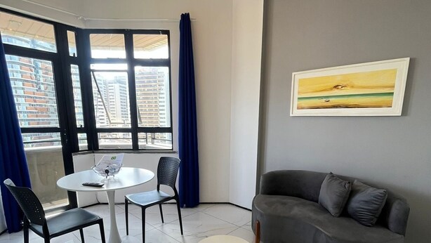 Ein modernes Wohnzimmer mit einem grauen Sofa, zwei runden Tischen und einem Gemälde an der Wand.