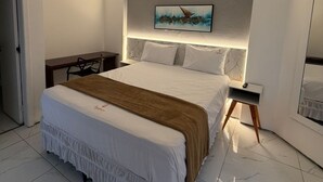 Ein modernes Schlafzimmer mit einem großen Bett, einem Schreibtisch und einem Bild an der Wand.