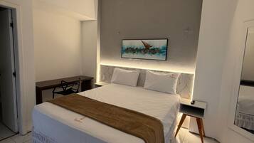 Quarto moderno com uma cama grande, uma escrivaninha e um quadro na parede.