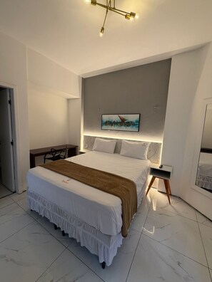 Ein modernes Schlafzimmer mit einem großen Bett, einem Schreibtisch und einem Bild an der Wand.