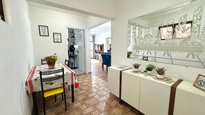 Un espace repas avec une table et des chaises, une cuisine en arrière-plan et un mur orné de tableaux encadrés.