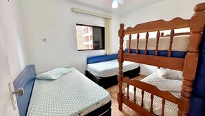 Une chambre avec deux lits, une fenêtre et un ventilateur de plafond.