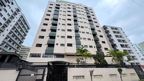 Un immeuble à plusieurs étages, doté d’une façade carrelée, de balcons et d’une entrée fermée par un portail.