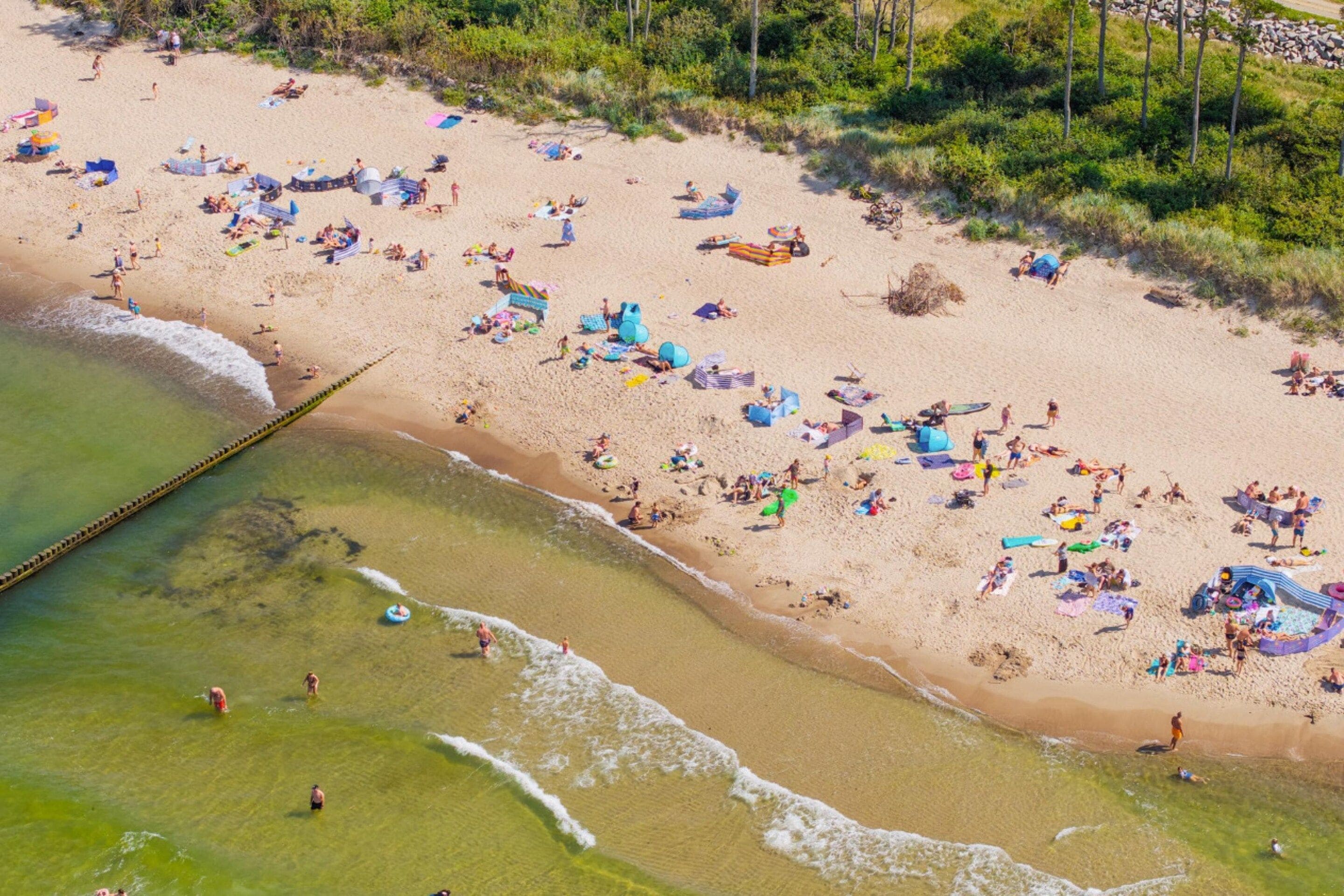 An aerial view of a beach with people, umbrellas, and beach equipment.