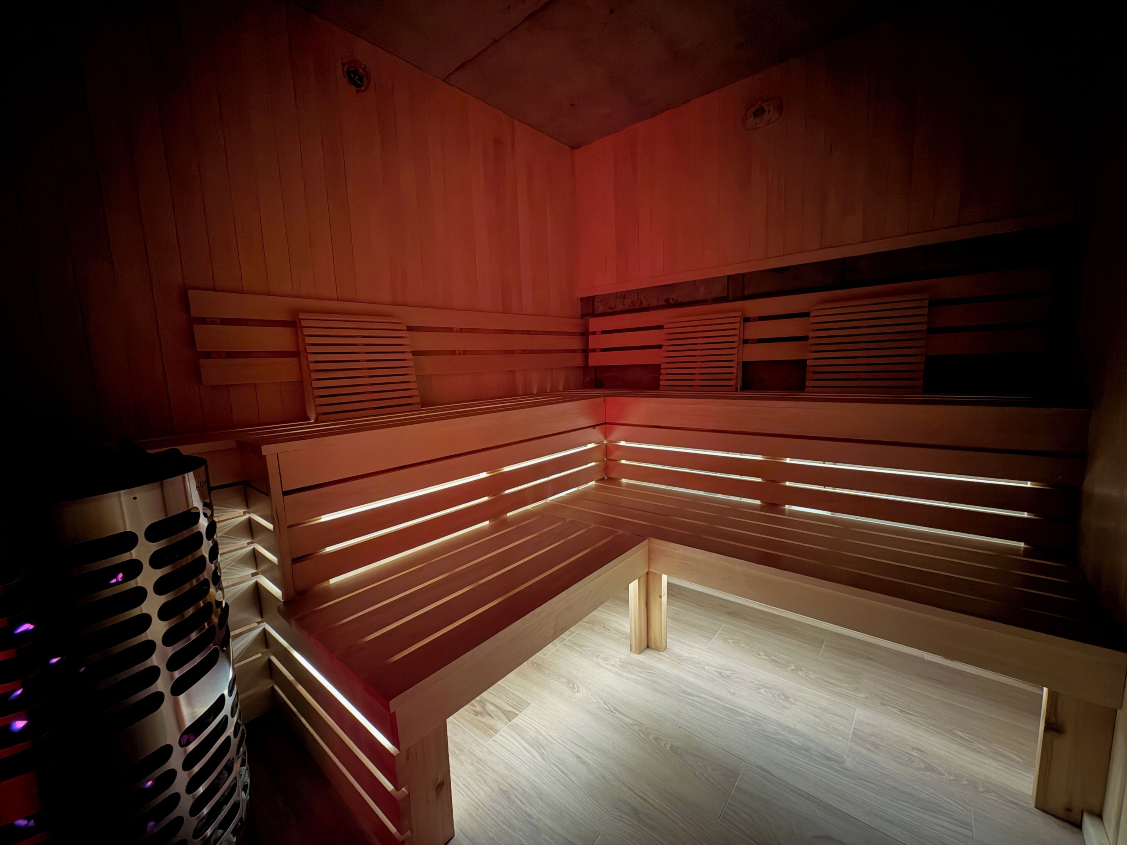 A sauna with wooden benches and a metal heater.