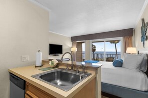 Ein Hotelzimmer mit Küchenzeile, einem Bett, einem Fernseher und Blick auf den Ozean.