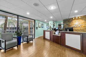 Ein Empfangsbereich mit einem Holzbüro, einem blauen Stuhl und einem Blumentopf.