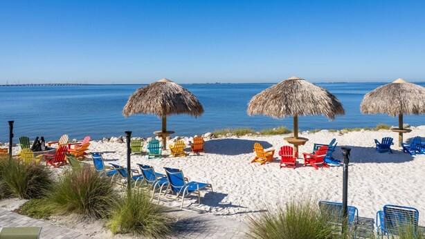 Ein Strand mit Reetsonnenstühlen, bunten Liegen und freiem Blick auf das Meer.