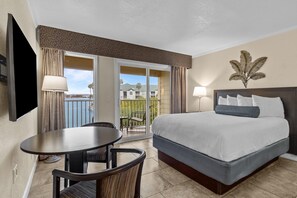 Ein Hotelzimmer mit Bett, Tisch, Stuhl, Fernseher und einem Balkon mit Blick.
