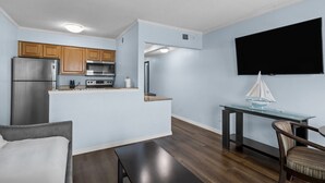 A compact living space with a kitchenette, a dining area, and a TV mounted on the wall.