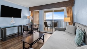 A hotel room with a balcony, a desk, a bed, and a TV.