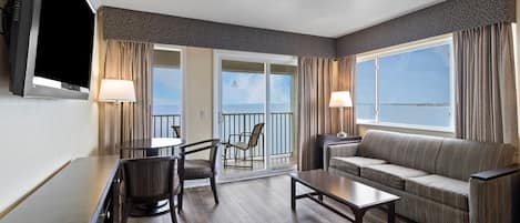 Quarto de hotel com varanda, sofá, mesa e cadeiras.