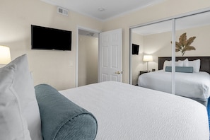 Une chambre d’hôtel avec un lit, une télévision, une porte et une table de chevet avec une lampe.