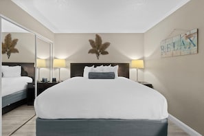Een hotelkamer met een groot bed, twee nachtkastjes met lampen, een spiegel en een wanddecoratie.