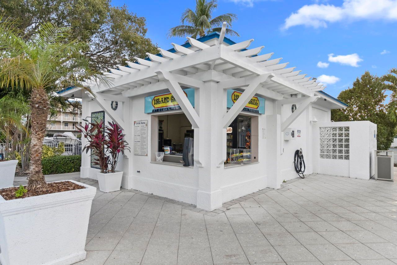 A white kiosk with a blue roof, labeled 'Island Grill,' featuring a counter and a small window display.