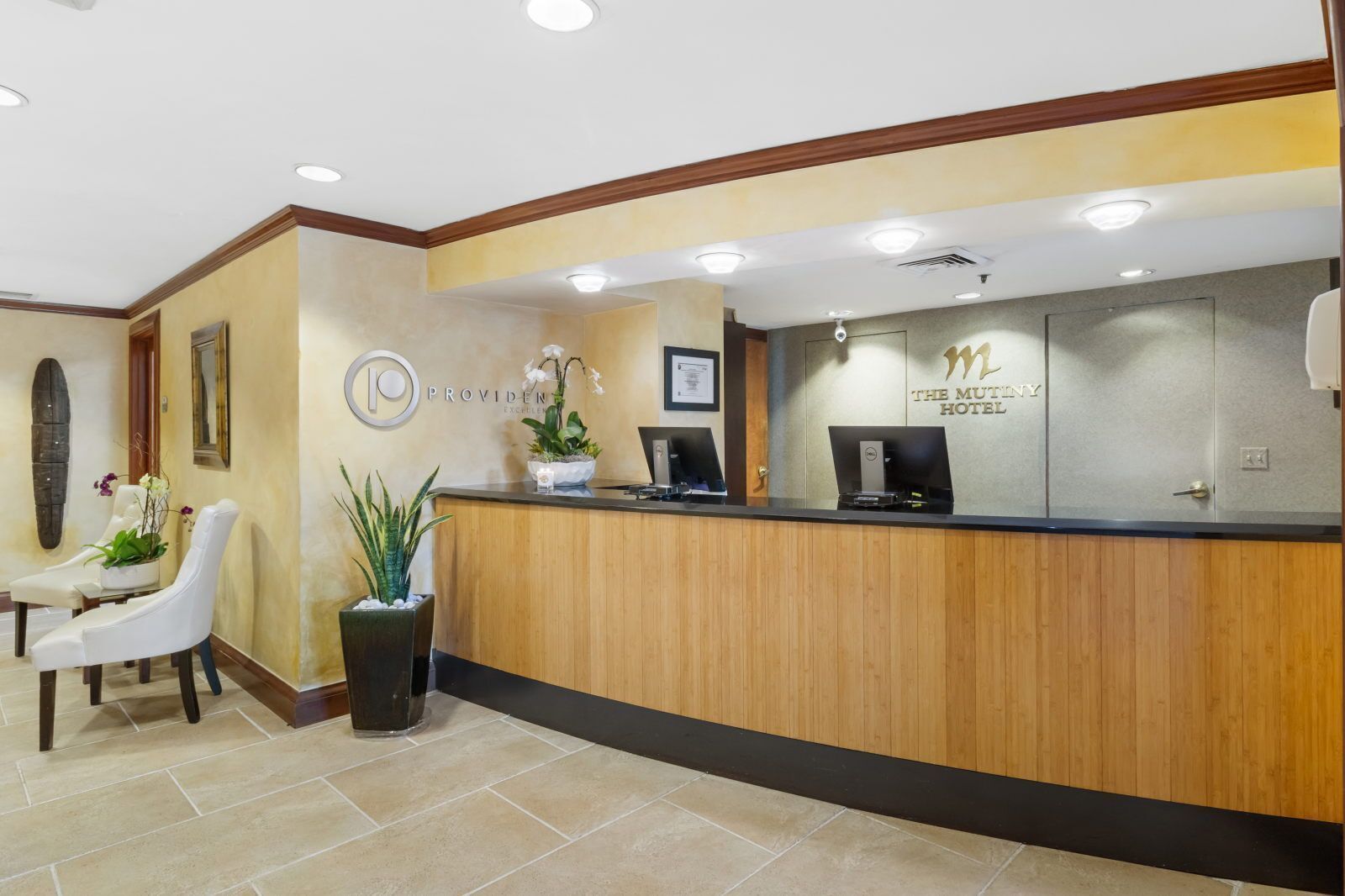 A reception desk with a wooden finish, a logo, and a sign for 'The Mutiny Hotel'.