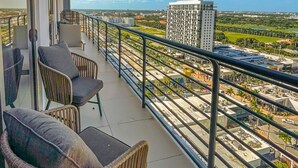 Un balcon avec des fauteuils en osier et une vue sur le paysage urbain.