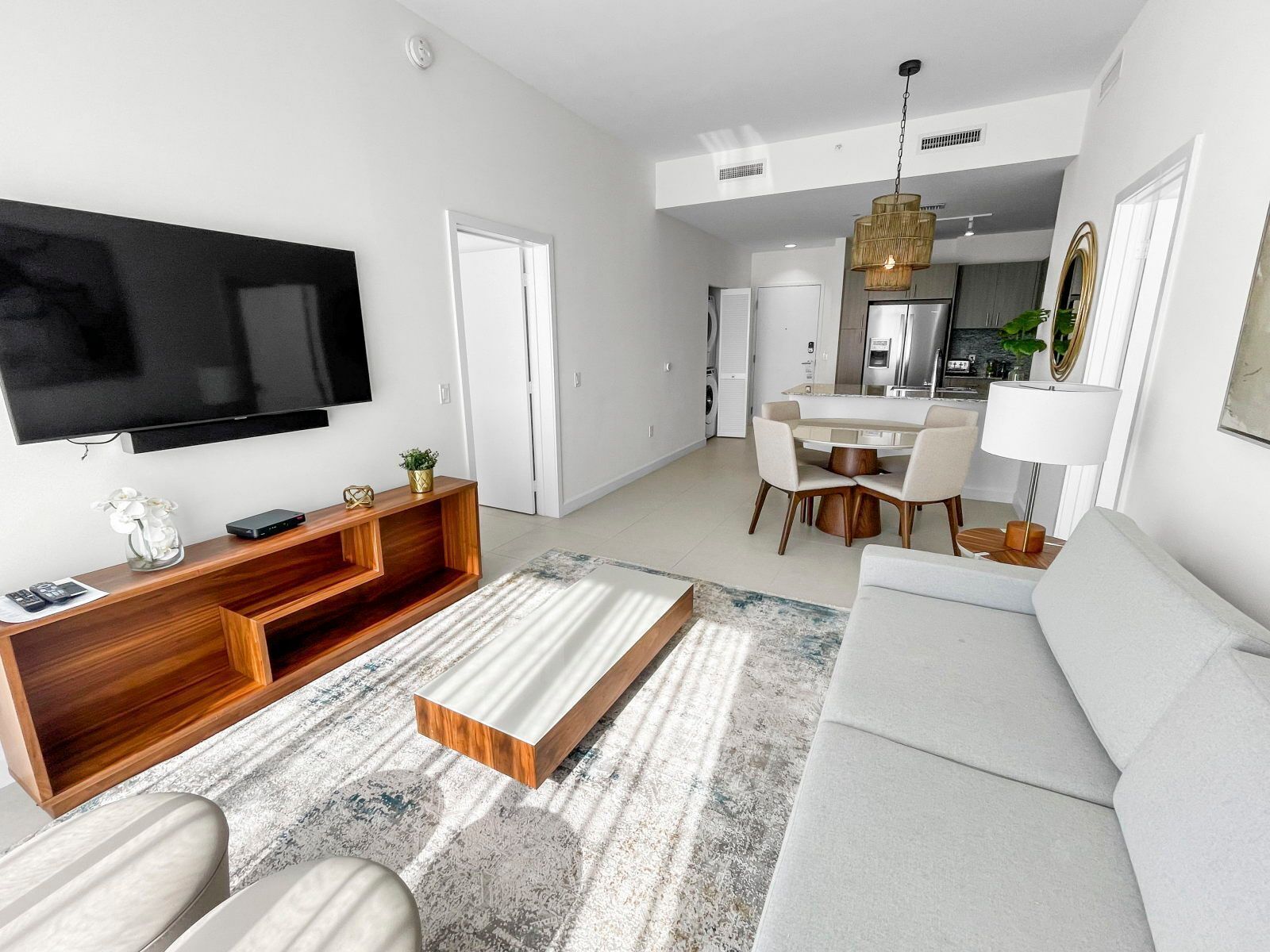 A modern living room with a flat-screen TV, wooden entertainment unit, and a sofa.