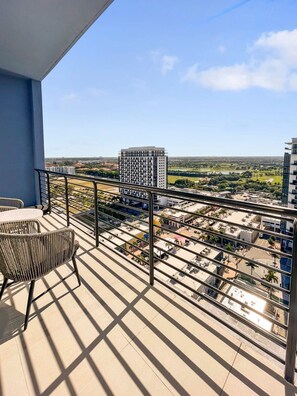A balcony with a view of a cityscape, including buildings and a park.