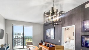 Een modern appartement met een eethoek, bank en uitzicht door een grote schuindeur.