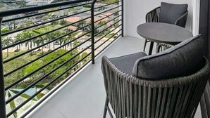 Un balcon donnant sur un paysage urbain, une table et deux chaises.
