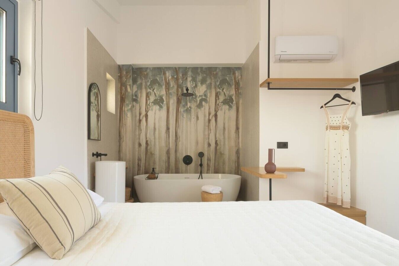 Ein Schlafzimmer mit einem großen Bett, einer Badewanne, einer Wand-Klimaanlage und einem Kleiderständer.