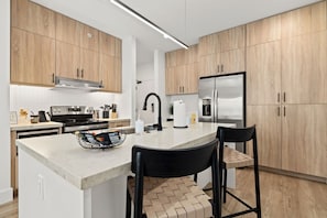Una cocina moderna con armarios de madera, electrodomésticos de acero inoxidable y encimera de mármol.