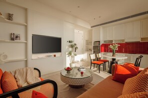 A modern living room with a TV, a round coffee table, and orange furniture.