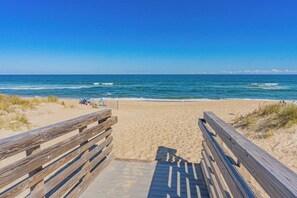 A wooden boardwalk leading to a sandy beach with the ocean in the background. - Return on Relaxation | Walk to Beach + Trails (Nags Head)