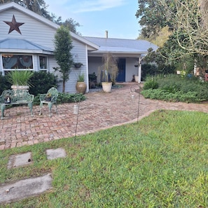 A house with a star on the roof, a brick pathway, and various potted plants.