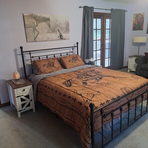 A bedroom with a bed, a nightstand, a window with curtains, and a wall painting.
