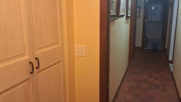 A hallway with a tiled floor, a white door with a handle, and a light switch on the wall.