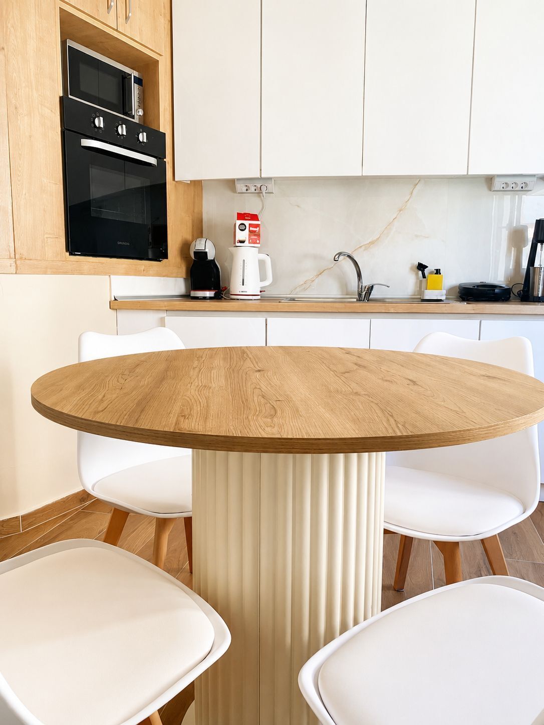 A modern kitchen with a built-in oven, a coffee maker, and a sink.