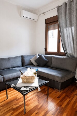 A modern living room with a gray sofa, a small table with a basket, and a window with curtains. - Bright and central apartment  (Voio)
