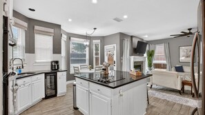 A modern kitchen with white cabinetry, a central island, and a dining area with a white table and chairs. - Private Pool | Fire Pit | Near Grapevine Lake (Flower Mound)