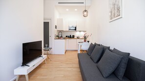 Ein modernes Wohnzimmer mit Flachbildfernseher, grauem Sofa und einem kleinen Beistelltisch.