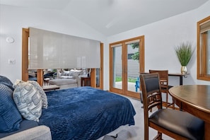 Un dormitorio con cama, sofá, mesa de comedor y una silla.